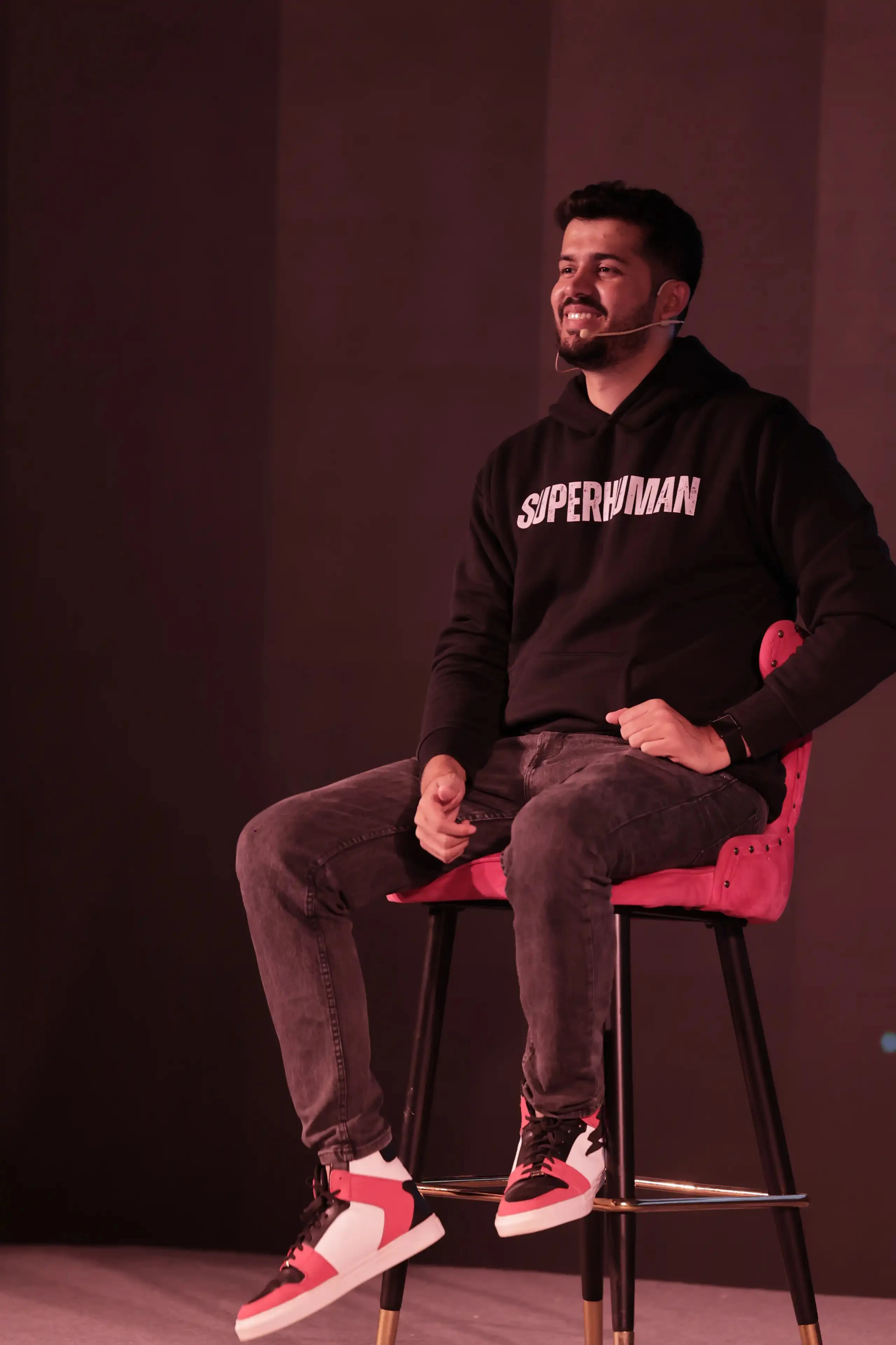 Swastik Nandakumar seated on stage at a live event, wearing a Superhuman hoodie