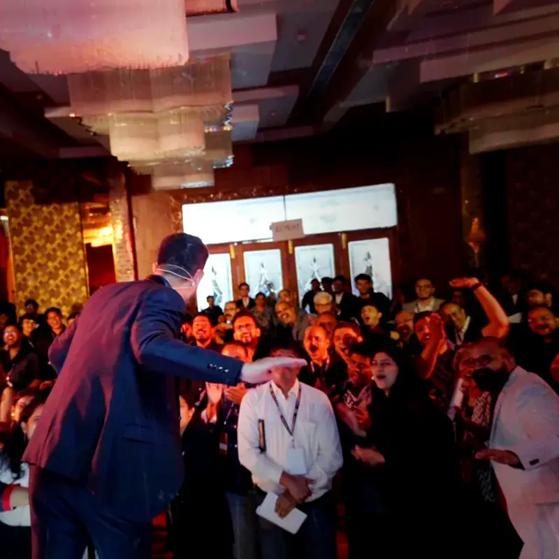 Swastik Nandakumar greeting a packed ballroom audience at a live event