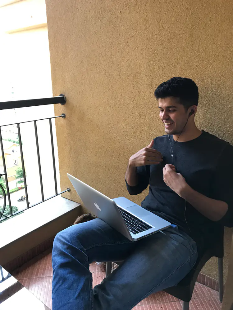 Swastik Nandakumar working on his laptop on a balcony